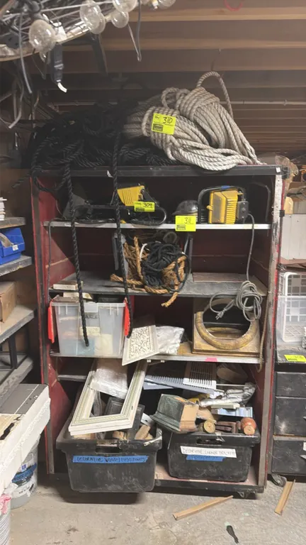 Multi-tier metal shelving unit. Features enclosed side and rear panels with multiple storage shelves. 48"W x 28"D x 72"H. Mounted on casters. Contents