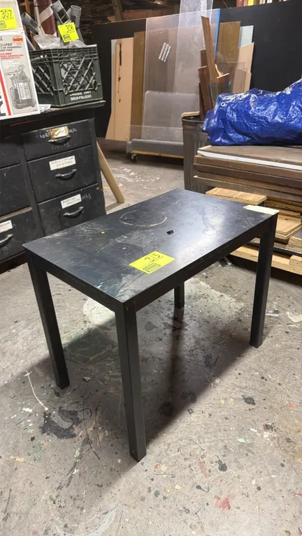 Metal table. Features black metal construction with square tubular legs. Dimensions: 28" x 18" x 24".
