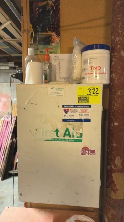Zee Medical wall-mounted metal first aid cabinet. Features a single hinged door with organizer pockets, 4 interior shelves, and assorted first aid sup