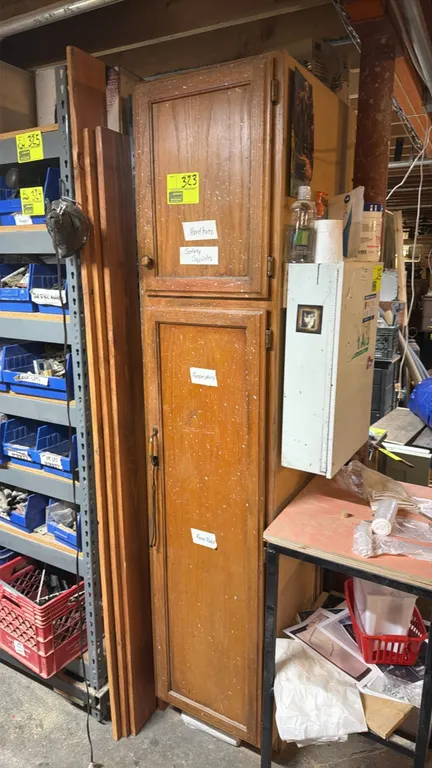 Two-door wood storage cabinet. Features upper and lower hinged cabinet doors with raised panel design and wood finish. Contents and attached side fixt
