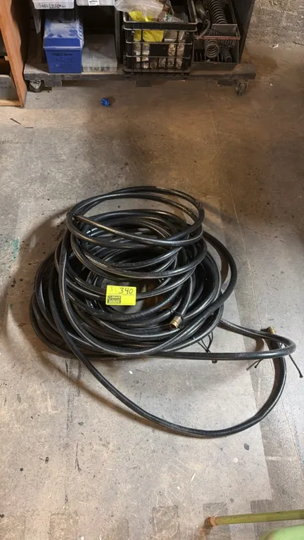 Assorted garden hoses. Features black rubber construction with threaded brass fittings.