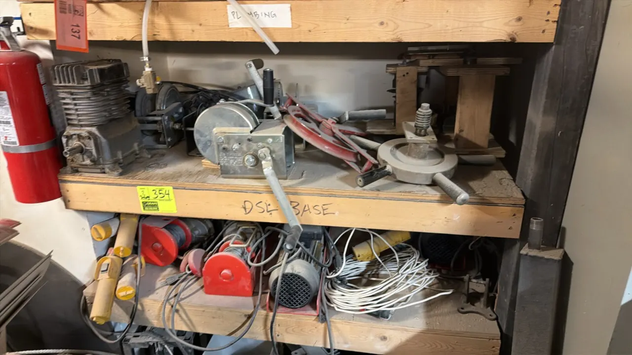 Assorted lot of electric and manual hoists, pulleys, and shop accessories. Includes electric cable hoists with wired pendant controls, manual hand-cra