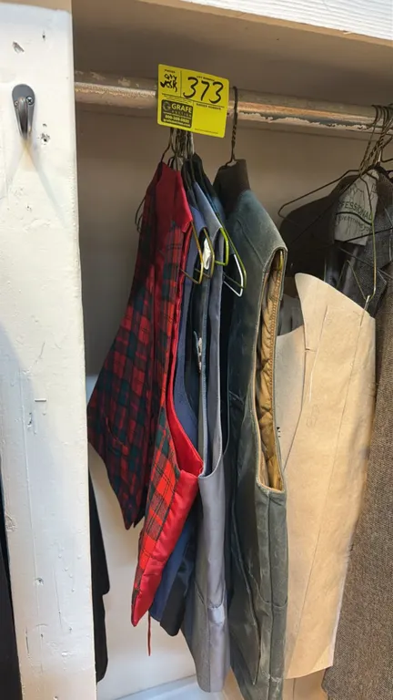 Assorted men's vests. Includes Filson zip-front waxed canvas vest with quilted lining, plaid formal vests, and a gray asymmetrical tailored suit vest.