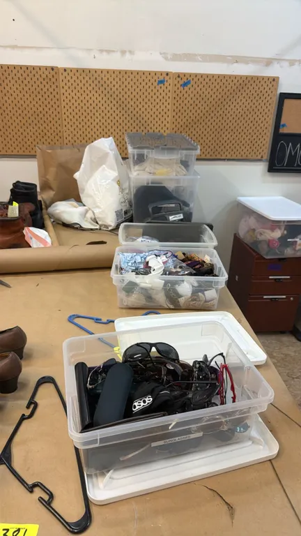 Package lot of assorted tabletop contents. Includes clear plastic storage totes with sunglasses and cases, costume jewelry, collar/cuff trims, ribbon