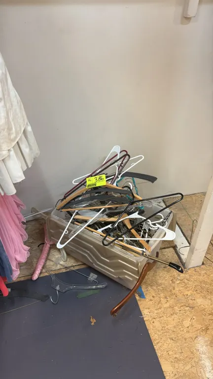 Assorted clothing hangers. Includes a variety of plastic, wood, wire, and clip styles. Housed in a plastic storage tote.