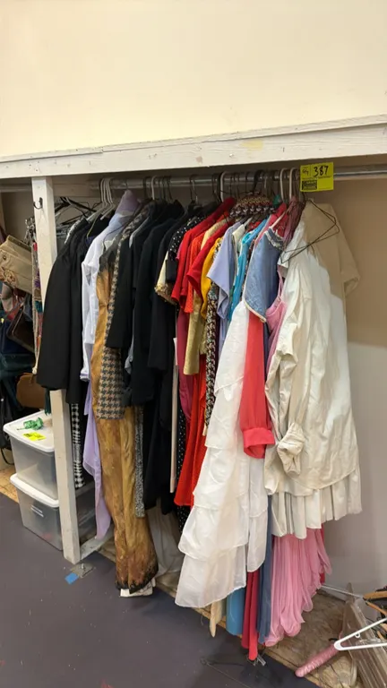 Assorted wardrobe clothing lot. Includes various dresses, shirts, tops, and theatrical garments in assorted styles, fabrics, and colors. Note: Hanging