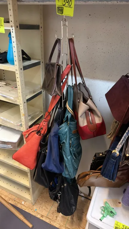 Assorted purses and handbags. Features various styles, colors, and materials, including shoulder bags, totes, and clutches. Note: Hanging display rack