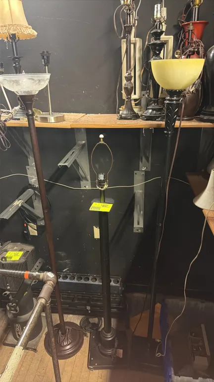 Assorted metal floor lamps. Includes (2) torchiere style lamps with glass shades (one frosted and one amber mottled) and (1) standard floor lamp with
