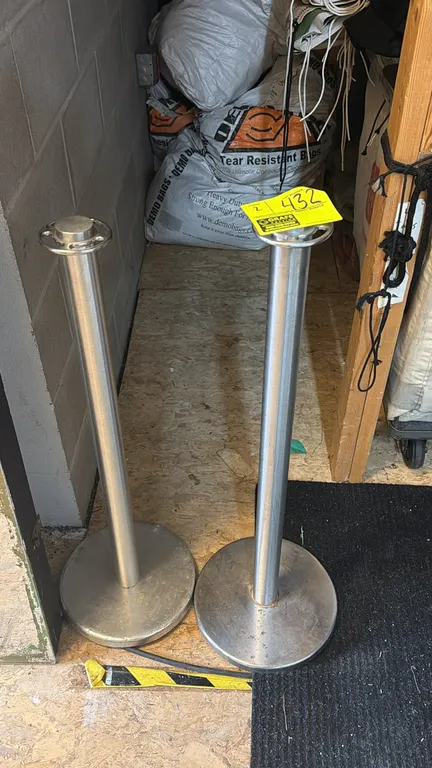 Metal crowd control stanchions. Features top ring collars for rope attachment and round weighted bases.
