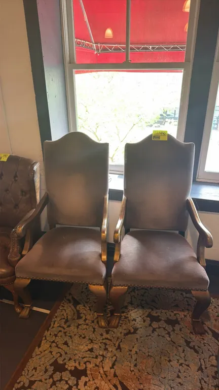 Cloth cushioned armchairs. Features high shaped backrests, padded fabric seats and backs, decorative nailhead trim, curved armrests, and gold-tone fin