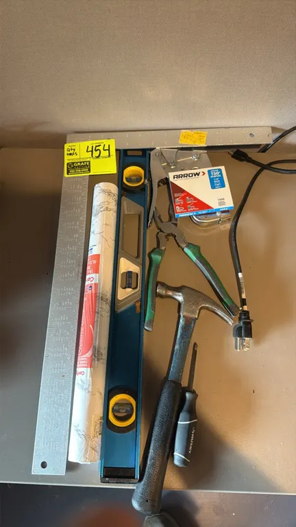 Assorted hand tools and accessories. Includes a metal framing square, spirit level, claw hammer, Husky screwdriver, pliers, Arrow staple gun with T50