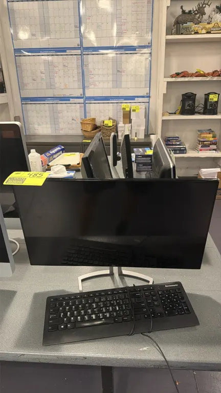 Dell widescreen computer monitor. Mounted on a silver-tone desktop stand. Includes a Lenovo wired keyboard.