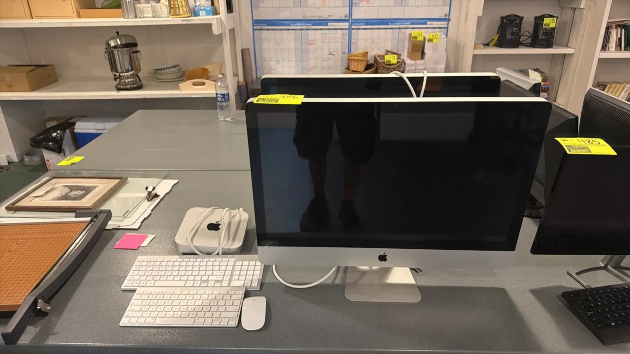 Apple computer setup lot. Includes (2) Apple flat panel monitors on aluminum stands, (1) Apple Mac mini computer with power cord, (2) keyboards, and (