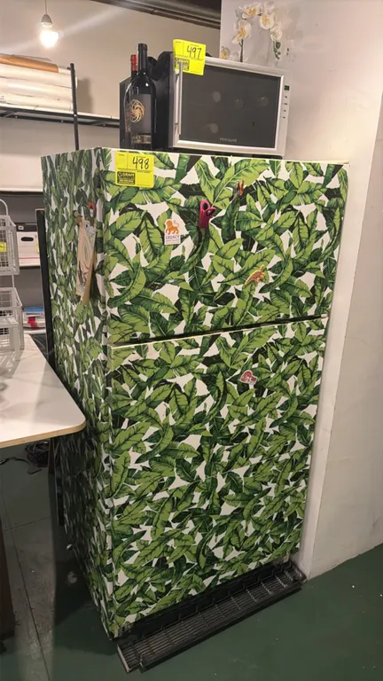Top-freezer refrigerator. Features top-mount freezer, lower refrigeration compartment, and a decorative tropical leaf patterned exterior wrap. Electri