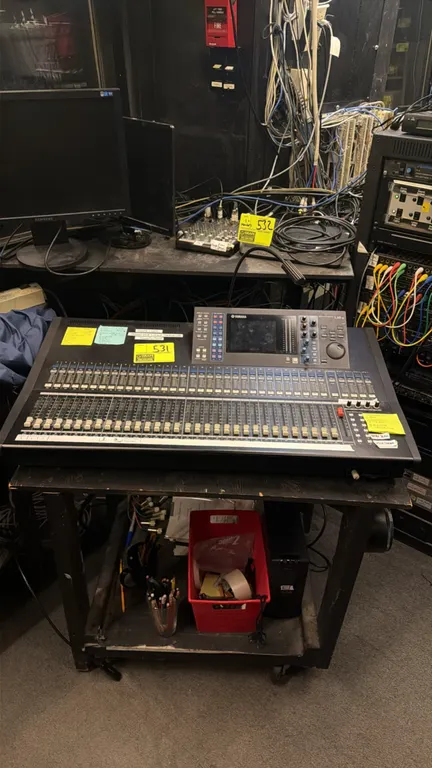 Yamaha LS9-32 32-channel digital mixing console. Features motorized faders, integrated display screen, and attached gooseneck console light. Includes