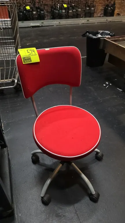 Cushioned office task chair. Features red upholstery with white piping trim, round cushioned seat, and armless design. Mounted on a 5-star base with c