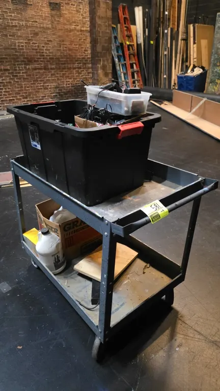 Metal 2-tier utility cart. Includes assorted electrical contents such as circuit boards, wiring harnesses, terminal lugs, charging cradles, and storag
