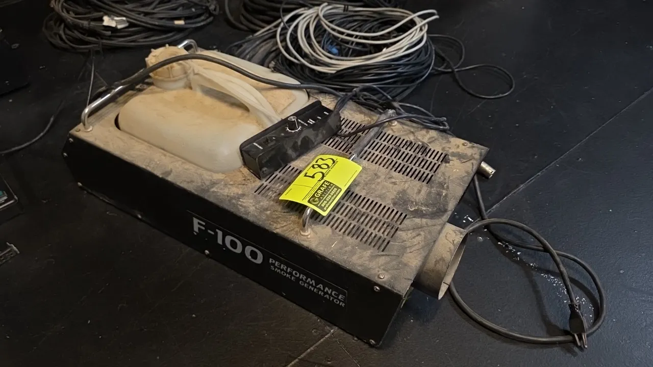 Performance F-100 smoke generator. Features integrated fluid reservoir tank, wired remote control module with fog volume adjustment dial, and metal tr