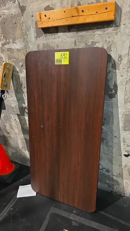 Laminate wood folding table. Features wood-grain laminate top with rounded corners. 48"L. Mounted on brown metal folding legs.