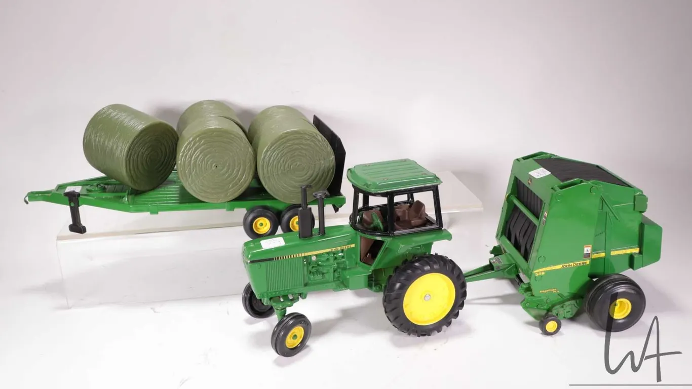 Three Ertl 1:18 scale die cast John Deere toys including 4450 tractor, 568 round bailer with hay bal
