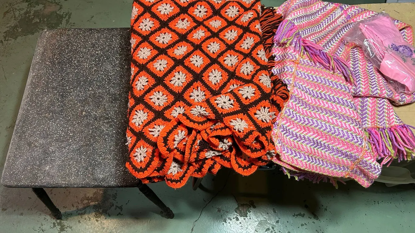 Brown Speckled Wooden Table with Crocheted and Woven Throw Blankets