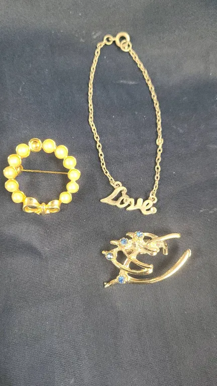 Three Costume Jewelry Pieces: Faux Pearl Pin, Gold-Tone Blue Rhinestone Brooch, and 'Love' Chain Bra