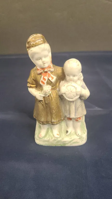Porcelain Figurine of Two Children, Painted Accents, Includes Handwritten Notes in Base Compartment