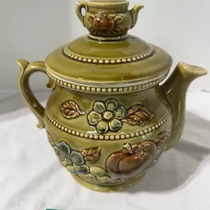 Vintage green ceramic teapot-shaped cookie jar with a smaller teapot lid.