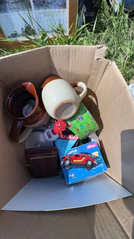 Box Lot with Stoneware Jugs, Toy Car, DVDs, Tin, and Sign
