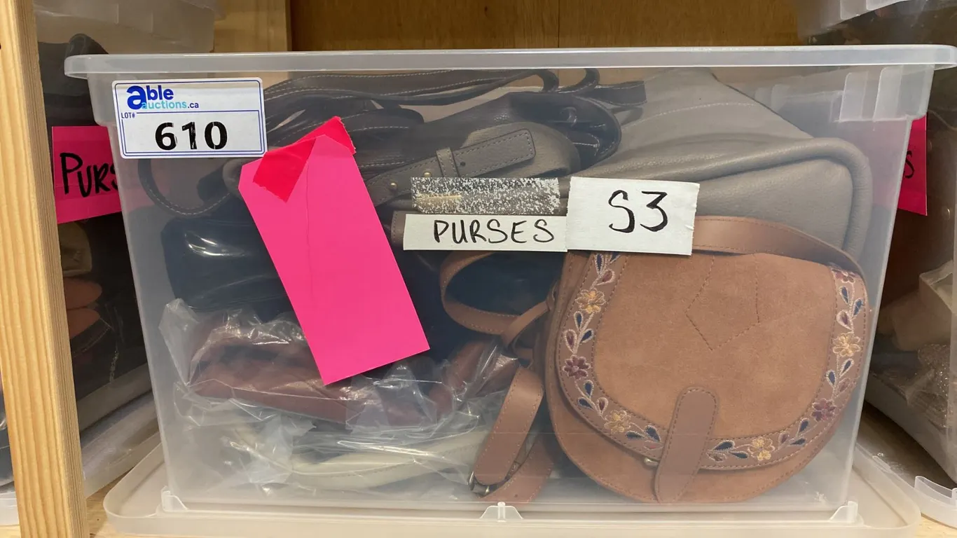 ONE PLASTIC STORAGE BIN OF ASSORTED PURSES