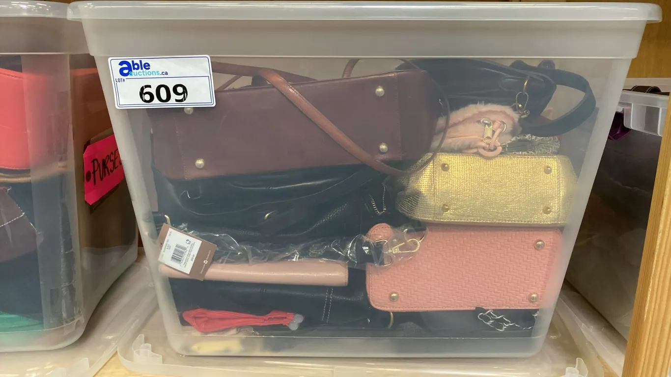 ONE PLASTIC STORAGE BIN OF ASSORTED PURSES