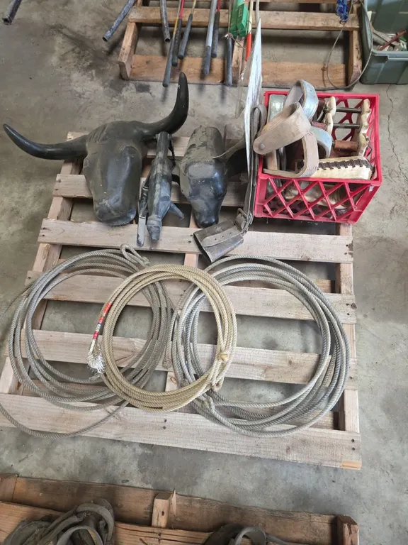 Pallet of lariats, roping dummys, cowbell and tote of stirrups
