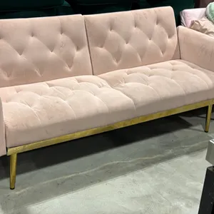 Upholstered loveseat. Features light pink tufted fabric upholstery, split-back design, and gold-tone metal base trim. 69"L. Mounted on tapered gold-to