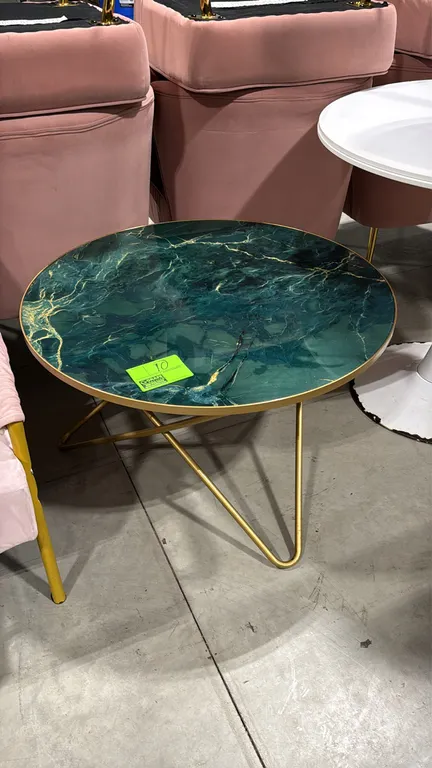 Round coffee table. Features a green and gold marble-pattern top with gold-tone metal edge trim. Mounted on a gold-tone hairpin-style metal base. 31.5