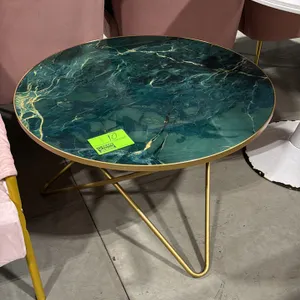 Round coffee table. Features a green and gold marble-pattern top with gold-tone metal edge trim. Mounted on a gold-tone hairpin-style metal base. 31.5