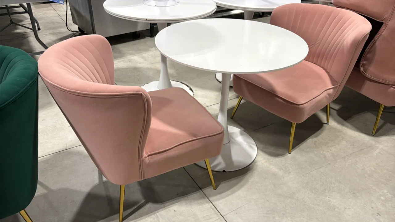 White pedestal table set with (2) pink fabric chairs. Includes a 31.5" round white top table on a tulip-style pedestal base, and (2) 22"W pink upholst