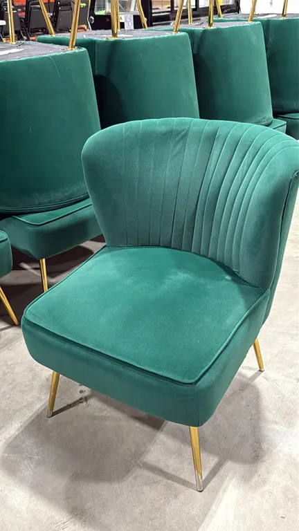 Green upholstered accent chair. Features channel-tufted backrest and cushioned seat. Mounted on tapered gold-tone metal legs. 22"W.