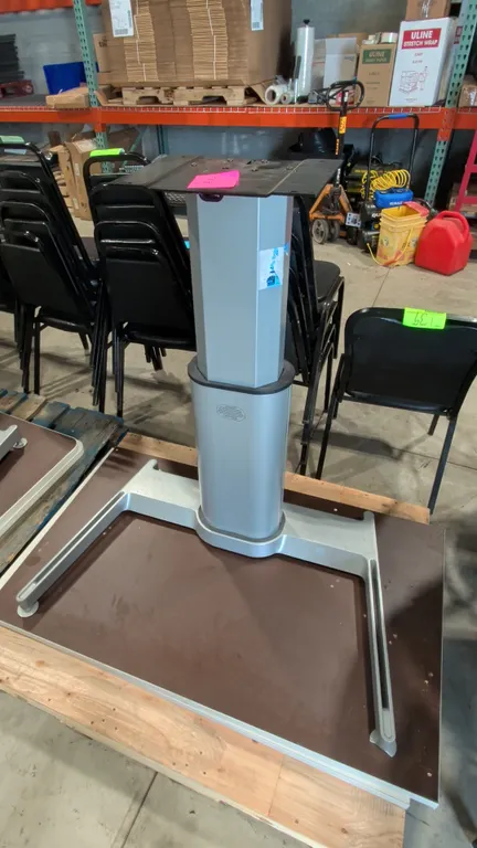 Pneumatic sit-stand desk base with two assorted tabletops. Features an adjustable height center pedestal column and silver-tone metal construction. Mo