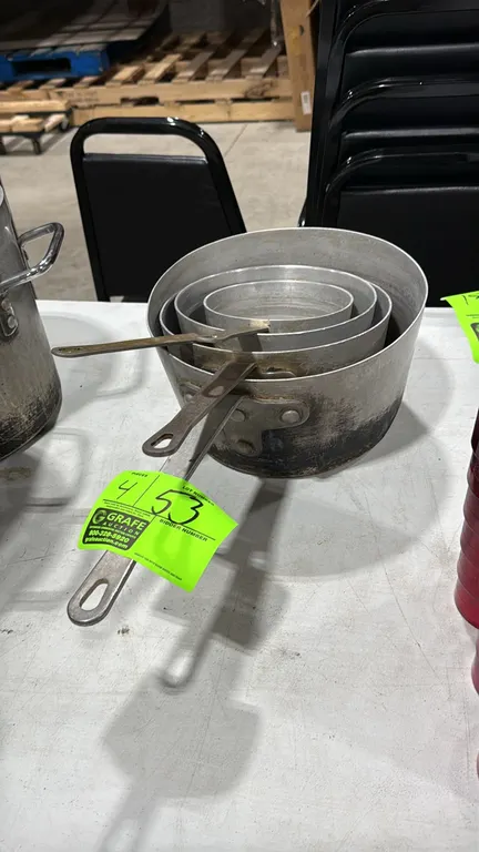 Assorted aluminum saucepans. Features heavy-duty aluminum construction with riveted flat handles.