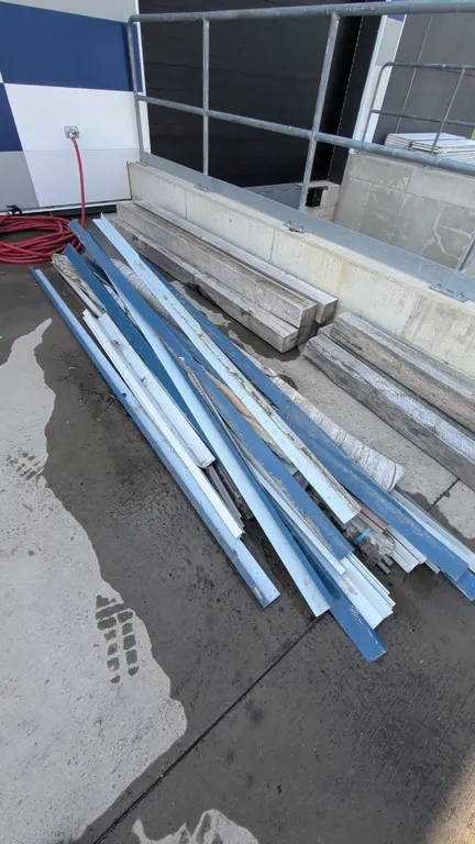 Assorted metal flashing and J-trim. Features assorted profiles, channels, and lengths in blue and white finishes. Note: Background items including woo