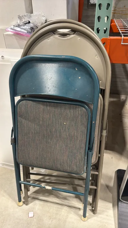 Assorted cushioned folding chairs. Features tubular metal frames with upholstered padded seats and folding design. Includes tan and teal colored units