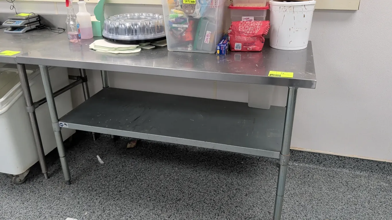 Stainless steel top work table. Features lower undershelf and tubular legs with adjustable bullet feet. 60"L. Contents not included.