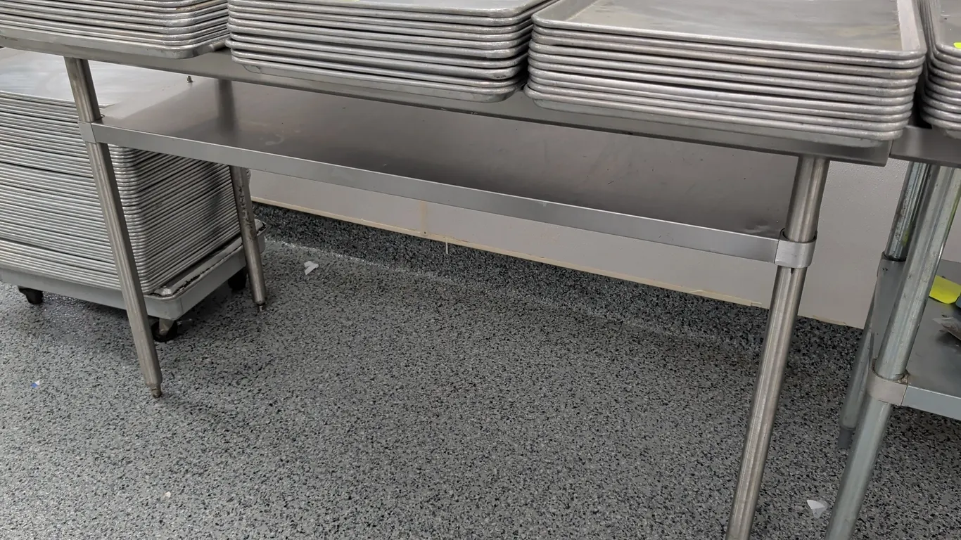 Stainless steel work table. Features stainless steel top and undershelf. 60"L. Mounted on tubular metal legs with adjustable bullet feet. Sheet pans n