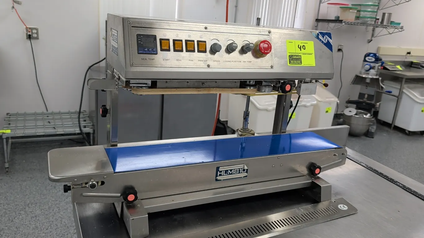 HL-M810 vertical dry ink continuous band sealer. Features stainless steel construction, integrated motorized conveyor belt, digital seal temperature c