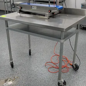 Stainless steel top work table. Features integrated backsplash and undershelf. 48" x 30". Mounted on casters. Sealer on table not included.