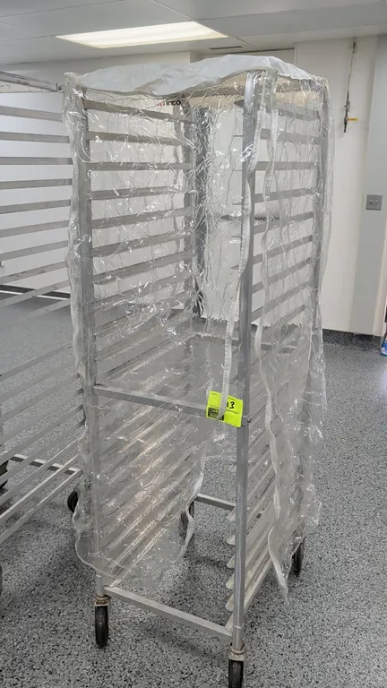 20-pan front load channel sheet pan rack with clear zippered cover. Accommodates 18" x 26" sheet pans. Features 20 slide tiers. Mounted on casters.