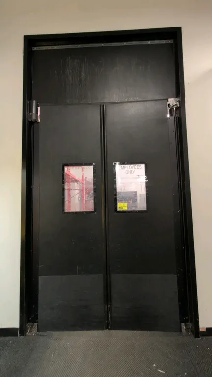 Polyethylene traffic swing doors. Features black poly panels, rectangular vision windows, lower kick plates, and mounting hinge hardware. 36"W x 105"H