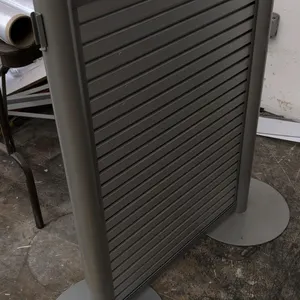 Metal retail display fixture. Features a horizontal slatted panel and dual tubular upright posts. 42" x 40"H. Mounted on circular metal disc bases.