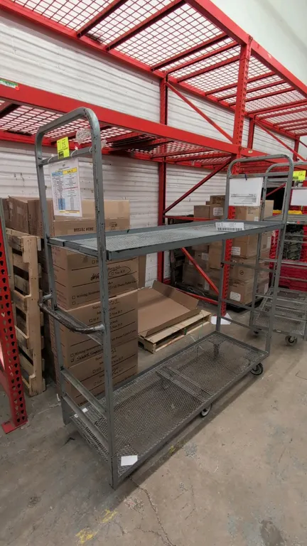 Metal 2-tier U-boat platform cart. Features expanded metal mesh shelves, tubular steel end frames, and integrated push handles. 5'L. Mounted on a 6-wh