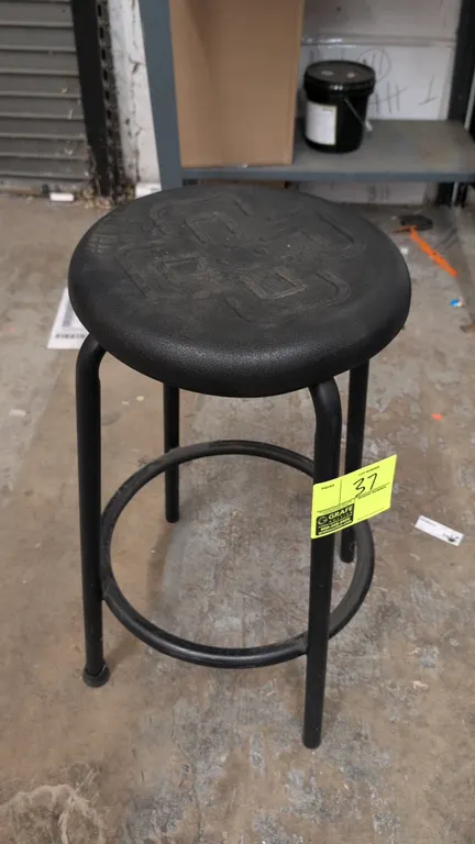 Foam cushioned stool. Features a round black molded foam cushioned seat and a black tubular metal 4-leg frame with an integrated circular footrest rin